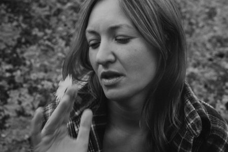 caucasian woman portrait holding feather, monochrome outdoors scene, storyteller pauses in meadow, close-upの写真素材