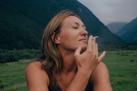 caucasian woman smelling mountain breeze, eyes closed and face tilted into wind, sensory awareness in lushの写真素材