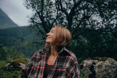 white woman smiling looking upward beneath trees, flannel shirt and open smile, forest therapy groundingの写真素材