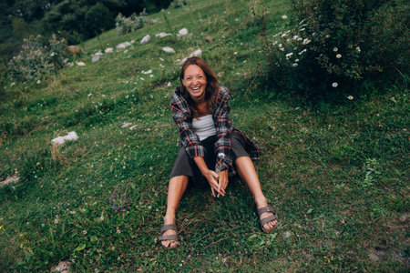 laughing woman reclining on grass, carefree picnic vibe with plaid shirt, warmの写真素材
