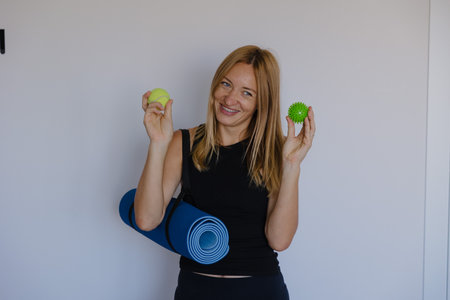 therapist holding two balls smiling teaching hand strength routine with blue mat tuckedの写真素材