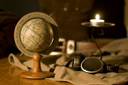 An old globe in a scene with a pair of flying goggles and a candleの写真素材