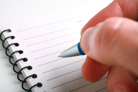 Close-up of hand with a pen on notepad