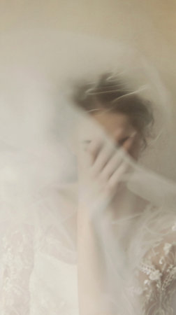 A blurred figure donning a white dress appears ethereally from muted shadows, with indistinct facial features and wide-open eyes amidst a foggy, dreamlike backdrop.の素材
