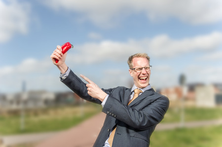 Blond german businessman in suit is lauging about the red pepper in his handの写真素材