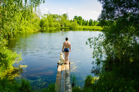 The child with the dog standing on the shore of lakeの写真素材