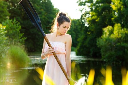 The girl floats down the river with a paddle in his handの写真素材