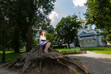 A girl with a book sitting under a tree in the background the Churchの写真素材