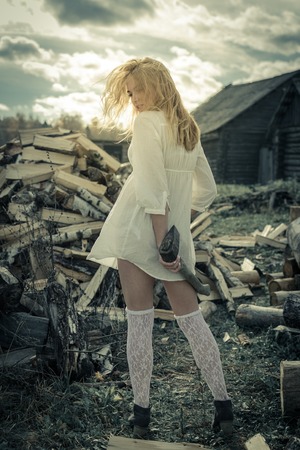The girl with the axe on the wood backgroundの写真素材