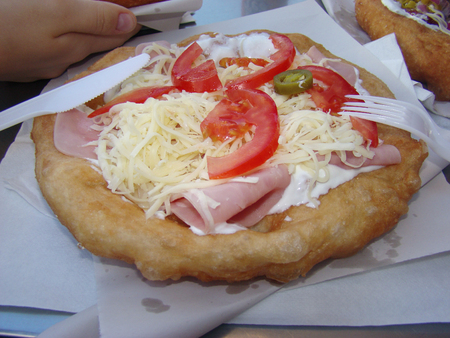 Fast food at an outdoor cafe, cake made of yeast dough with cheese, ham, tomatoes and jalapenosの写真素材