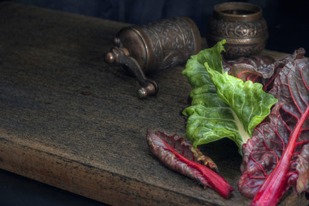 Fresh leaves of Swiss chard green and burgundy color on a dark wooden background. Vintage style....