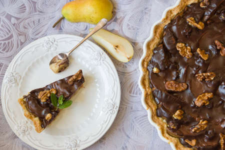 Chocolate pear tart. A portioned slice on a white plate. Daylight, selective focus, horizontal photoの写真素材