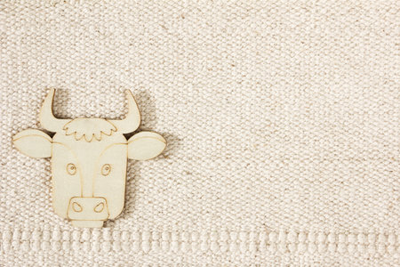 Natural cotton striped uncolored textured sacking burlap background with a wooden figurine of a cow....