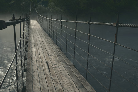 old wooden long suspension bridge over the Belaya mountain river, in nature, thick mystical fog over the water at night in the moonlightの写真素材