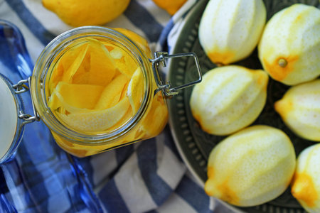 glass jar with lemon zest inside, next to fresh peeled lemons. selective focus. Preparation of...