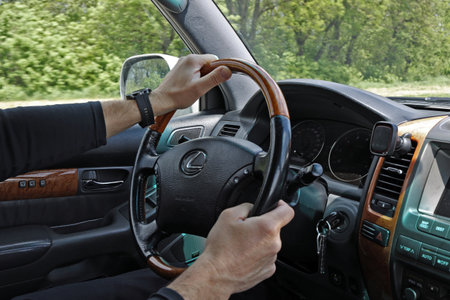 Male hands on the steering wheel of a Lexus GX-470 while the car is moving. Illustrative editorial of Lexus steering wheel close-up: Krasnodar, Russia- 11May 2022.のeditorial素材