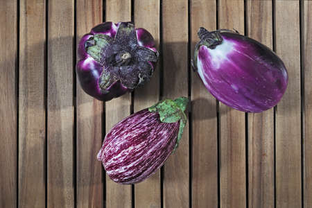 Composition of three round purple eggplants aubergine on wood backgroundの写真素材