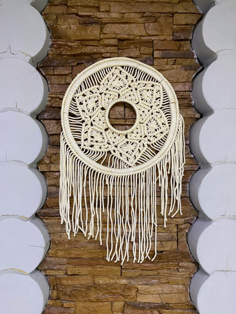 Handmade macrame folk art. The products are woven from rope, hanging against the background of a...