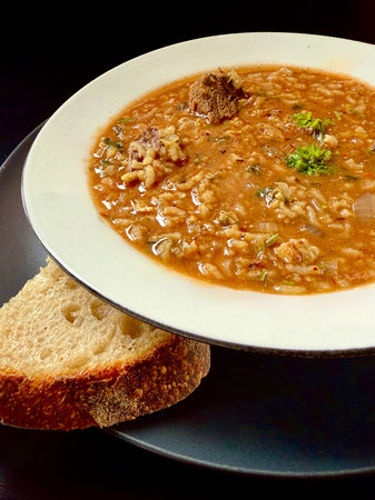 Georgian soup. Kharcho with rice, tomatoes, beef, garlic and herbs in the plate on black table...