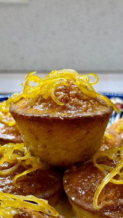 Freshly baked homemade lemon muffins, drizzled with lemon glaze and garnished with lemon zest