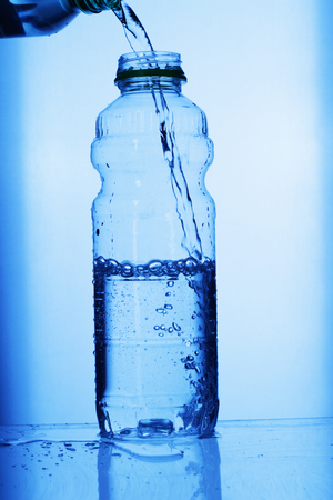pouring water into the bottleの写真素材