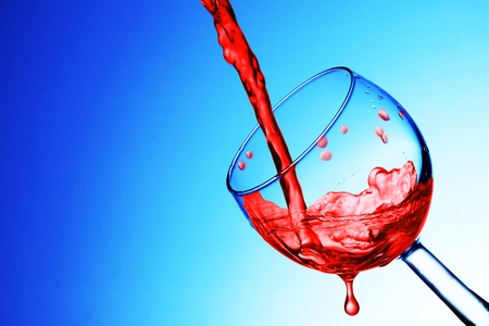 pouring wine into a glass on a blue backgroundの写真素材