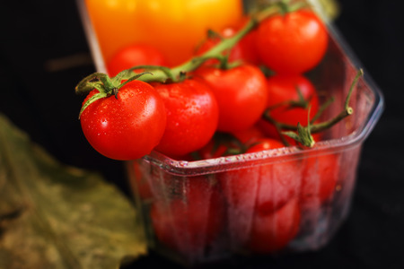 cocktail tomatoes on a black background with yellow peppersの写真素材