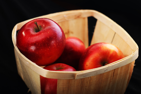 red apples in a basket on a black backgroundの写真素材
