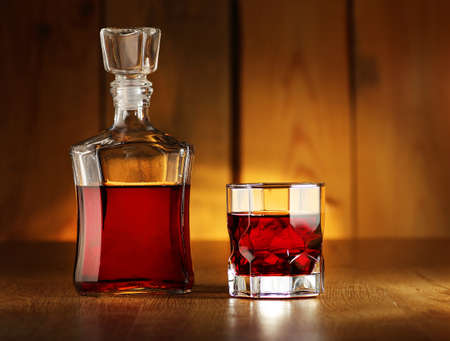 carafe with a tincture and a glass for drinks on the background of wooden boardsの写真素材