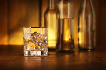 drink glass with rum and ice cubes on the background of wooden boardsの写真素材