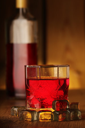 glass for drinks with red vodka on the background of the bottle and woodの写真素材
