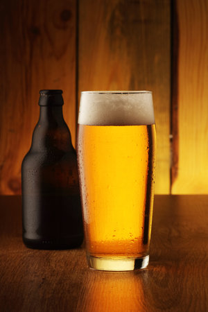 mug with beer and bottle on boards and wooden background
