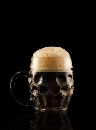 glass mug with handle and dark beer on a black backgroundの写真素材