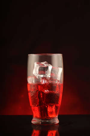 glass with alcohol and ice cubes on black background and red gradientの写真素材