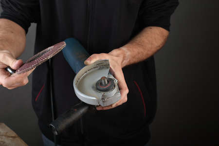 the person holds an angle grinder in his hands on a gray backgroundの写真素材