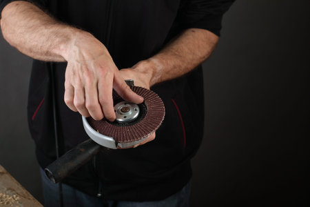 the person holds an angle grinder in his hands on a gray background