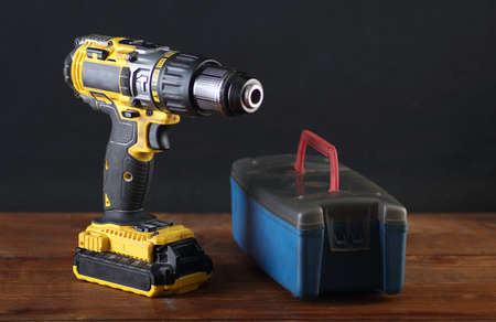 yellow screwdriver with a box of drill bits on the table and gray backgroundの写真素材