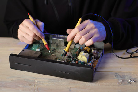 repair of an old satellite tuner by person on the table and gray background