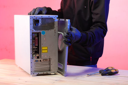 disassembly of an old desktop computer by a person on a table and a pink background