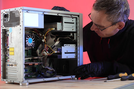 disassembly of an old desktop computer by a person on a table and a pink backgroundの写真素材