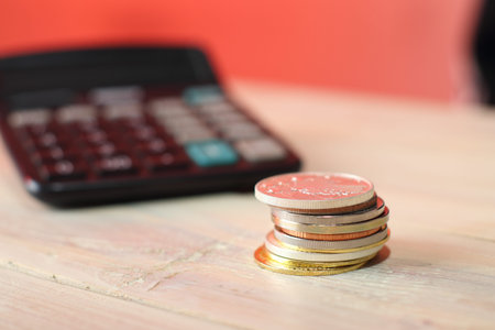 pile of coins on the table and background from a calculator and a colored wall