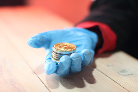 large colored coins in gloved hand over table and violet background