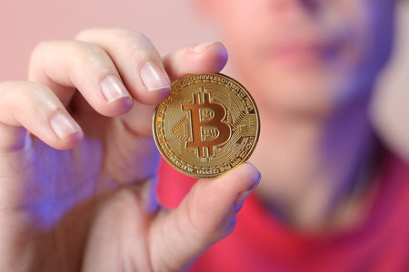 a person holding a coin in his right hand on a colored backgroundの写真素材