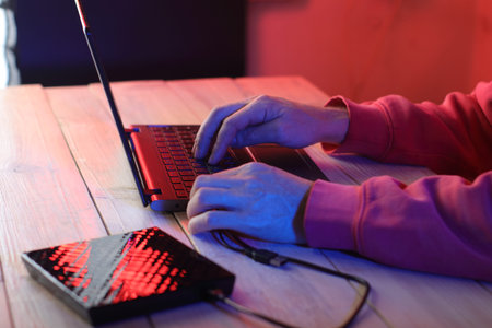 laptop with attached optical drive on the table in front of a person on a colored background
