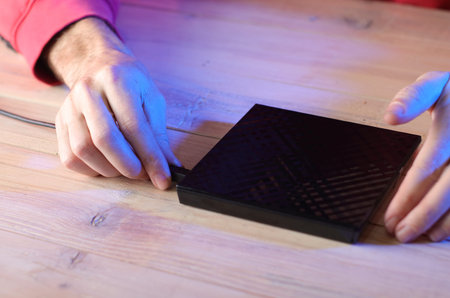 connecting the cable to the optical drive from the laptop on the table by a person in a red...