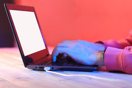 typing on laptop with usb cable and blank screen on table and colored backgroundの写真素材