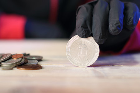 silver australian dollar with a kangaroo under the finger on the table next to the coins against the background of the silhouette of a personの写真素材