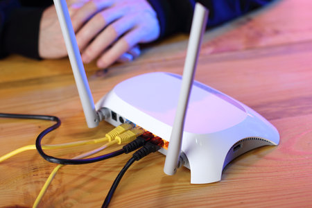 router with connected internet cables on table and person's handsの写真素材