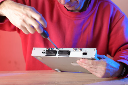 disassembly of an old tv tuner by a person in a red sweatshirt and a colorful background