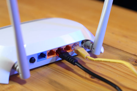 back of router with ethernet ports and connected cables on wooden table